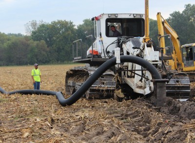 Jarod Parkhill (in plow) installs drainage tile near Harrisonville, Missouri with Dustin Hall (left) looking on.